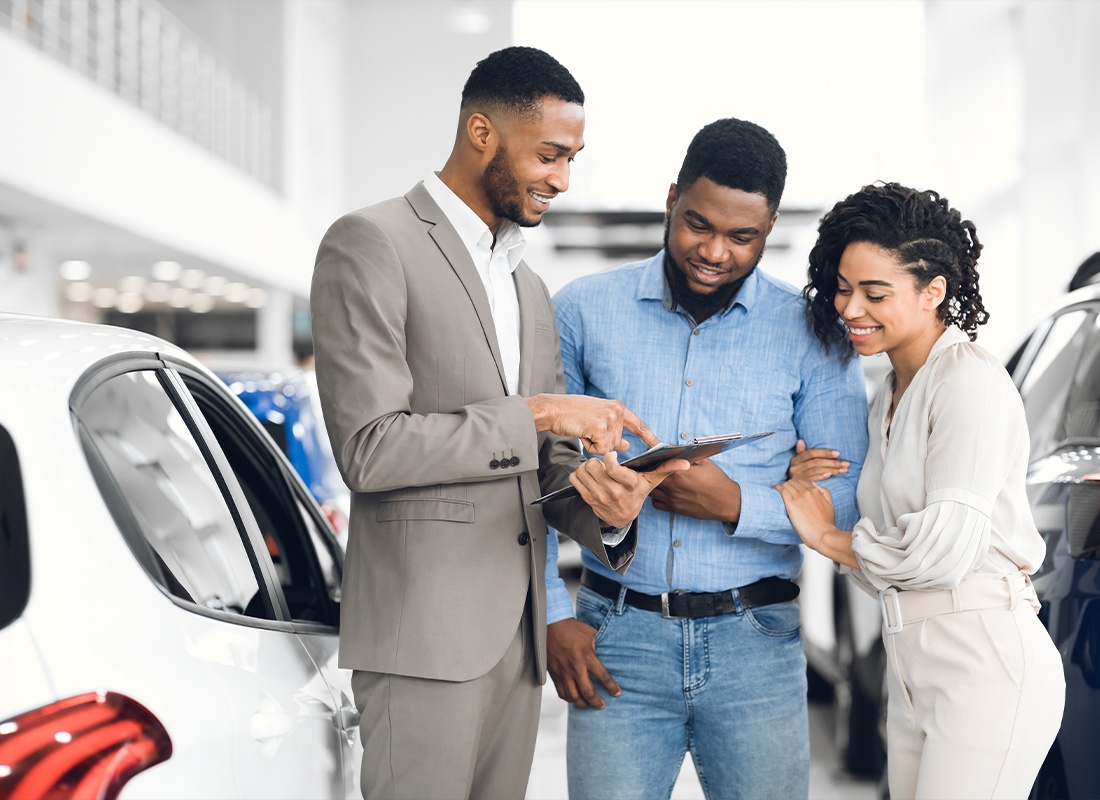 Insurance by Industry - A Young Couple Going Over Car Options With a Salesman at the Dealership